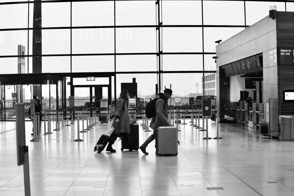 People walk through an airport terminal with luggage.