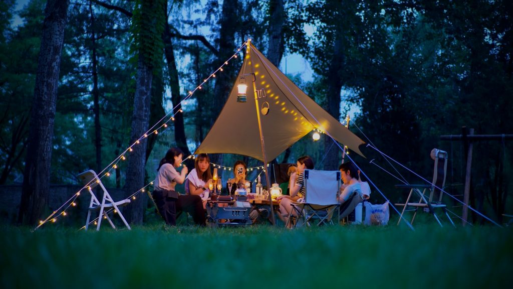 a group of people sitting around a tent in the woods